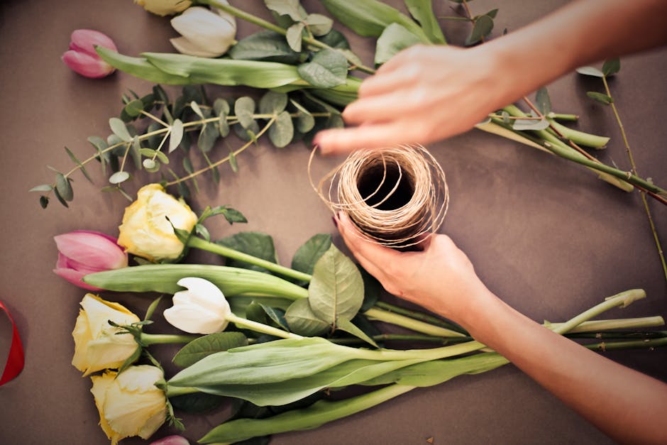 A vibrant display of fresh floral arrangements at a flower market, featuring yellow sunflowers, small white daisies with yellow centers, and other mixed blooms wrapped in brown craft paper. Prominent 